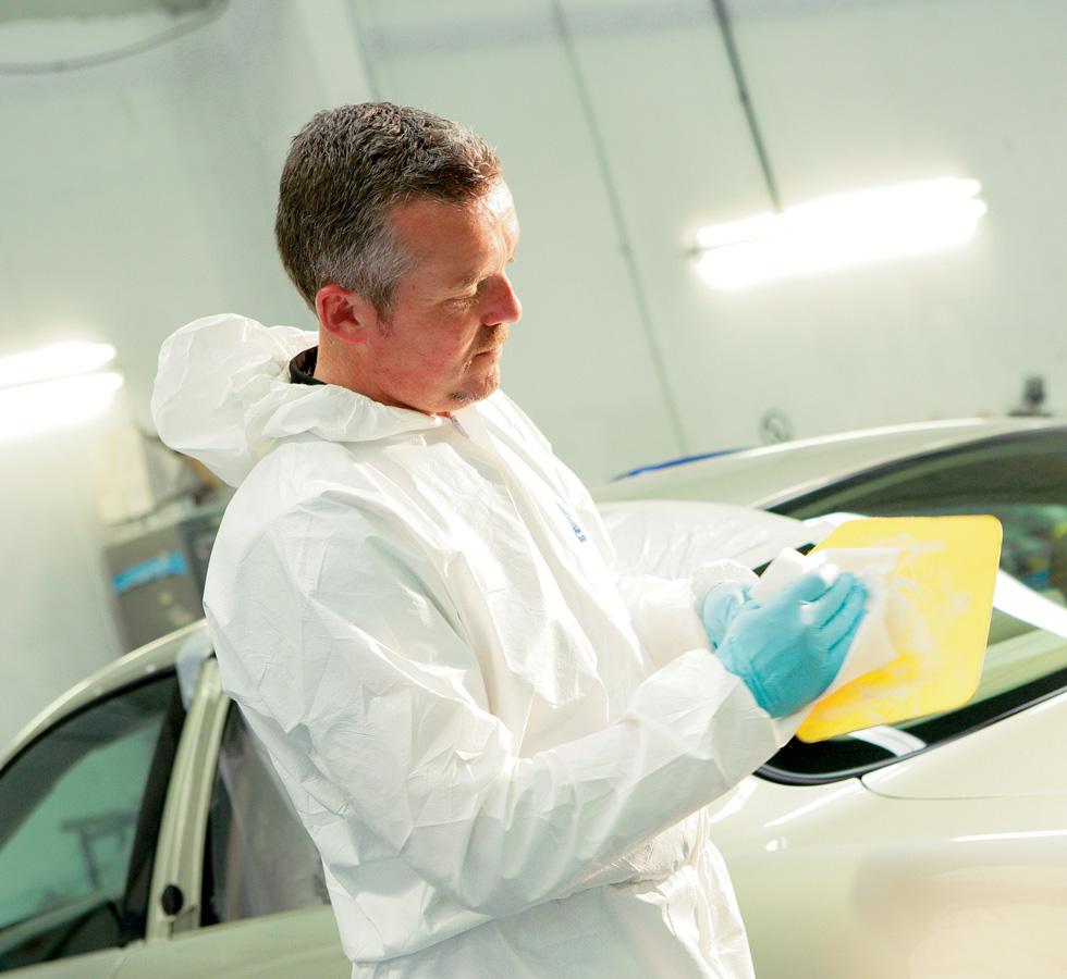 A Man in a White Coverall and Blue Gloves Using a White 7642 KIMTECH* Sealant Wipers on Yellow - White - Sentinel Laboratories Ltd