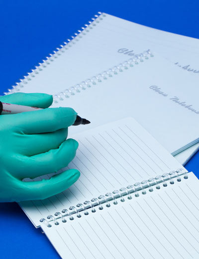 A Person With a Green Gloved Hand Writing on a Page from a Ansell BioClean Notebooks Cleanroom Notebook