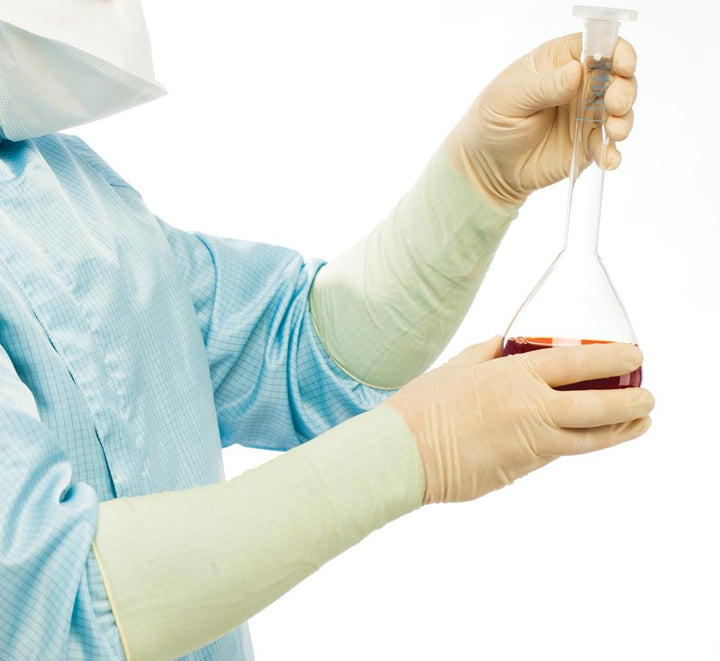 A Person in a Blue Lab Coat Wearing a Pair of Light Tan Coloured Long Length Cuff BioClean Extra™ Sterile 400mm Length Latex Gloves Holding a Vial of Brown Liquid - Sentinel Laboratories Ltd