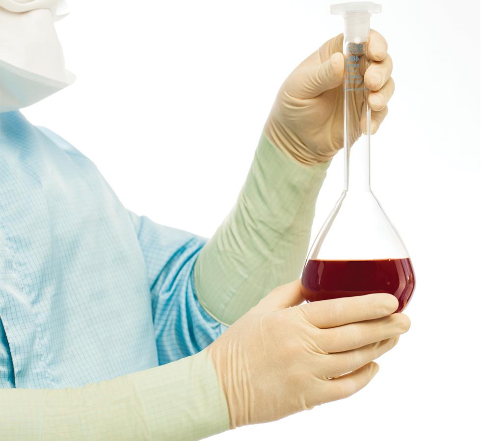 A Person in a Blue Lab Coat Wearing Tan Coloured BioClean Legion™ Non-Sterile 400mm Length Latex Long Length Cuff Gloves Holding a Vial of Red Liquid - Sentinel Laboratories Ltd