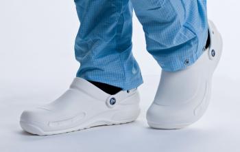 A Person in Blue Trousers Wearing a Pair of White Crocs for Cleanroom Use