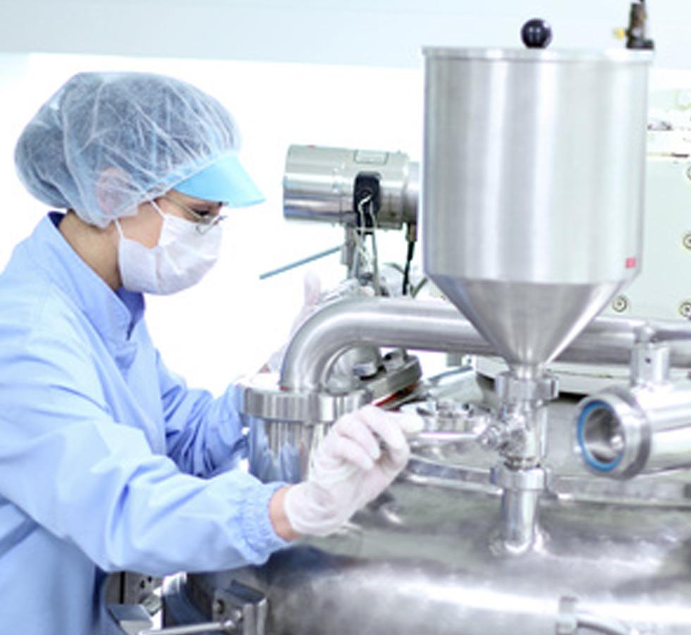 Woman in blue gown wearing a hair net masks and gloves using machinery - Health and Safety for Manufacturing - Level 1 - Sentinel Laboratories Ltd