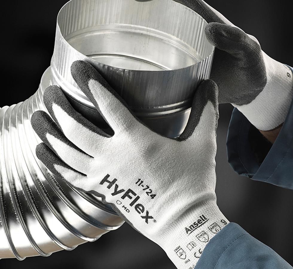 A Person Wearing Black and White HYFLEX® 11-724 Gloves Holding a Large Ribbed Metal Tube - Sentinel Laboratories Ltd