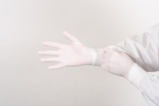 A Person in a White Coverall Donning a Pair of White Bioclean NAN 5 Nitrile Cleanroom Gloves