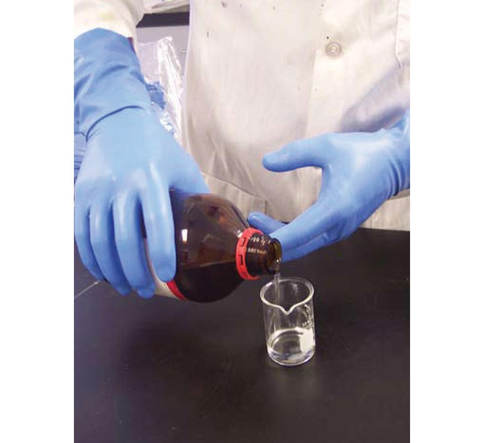 A Person in a White Lab Coat Wearing a Pair of Blue Showa Best 707 Nitri-Dex™ Nitrile Gloves with Long Length Cuffs Pouring Clear Liquid from a Brown Bottle into a Flask - Sentinel Laboratories Ltd