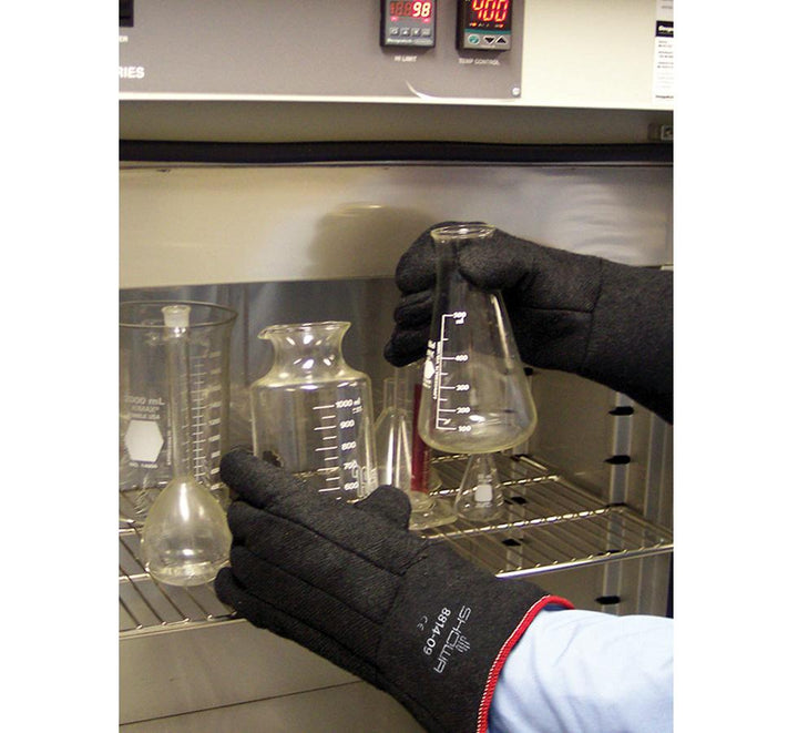 A Person Wearing a Pair of Black Showa Best 8814 Charguard® Heat Resistant Gloves 355mm long holding a Variety of Flasks - Sentinel Laboratories Ltd