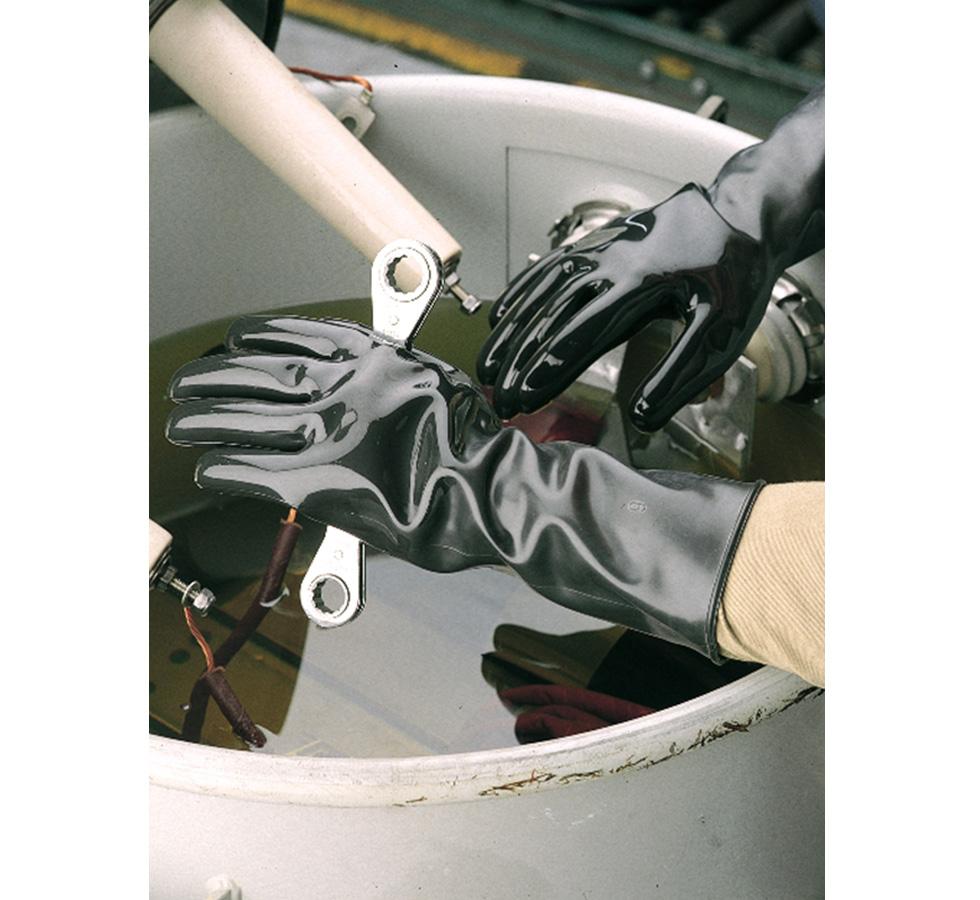 A Person Wearing a Pair of Shiny Black Showa Best 890E Best Viton Unlined Viton over Butyl Gloves with Long Length Cuffs with a Wrench over a Barrel of Oil, 0,70mm Thick - Sentinel Laboratories Ltd