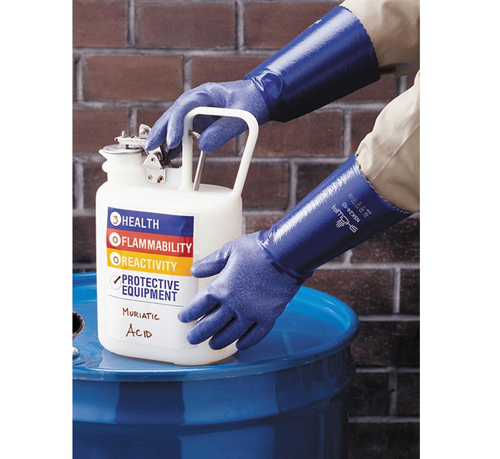 A Person Wearing a Pair of Long Cuff Length Blue Showa Best NSK24 Nitrile Coated, Cotton Interlock Liner, 100% Nitrile Gloves Handling a White Container of Muriatic Acid - Sentinel Laboratories Ltd