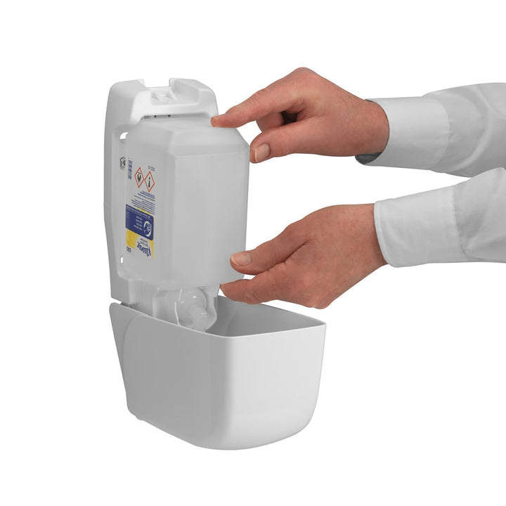 A Person Inserting a Clear, White and Blue Refill Pack Into an Open 6382 Hand Sanitiser Dispenser