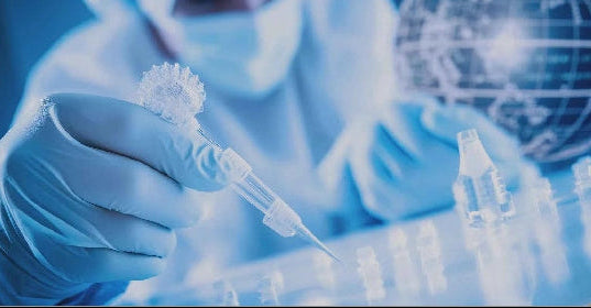 A Person in a Blue Lab Coat, Mask and Gloves Using a Clear Pipette in a Blue Lab