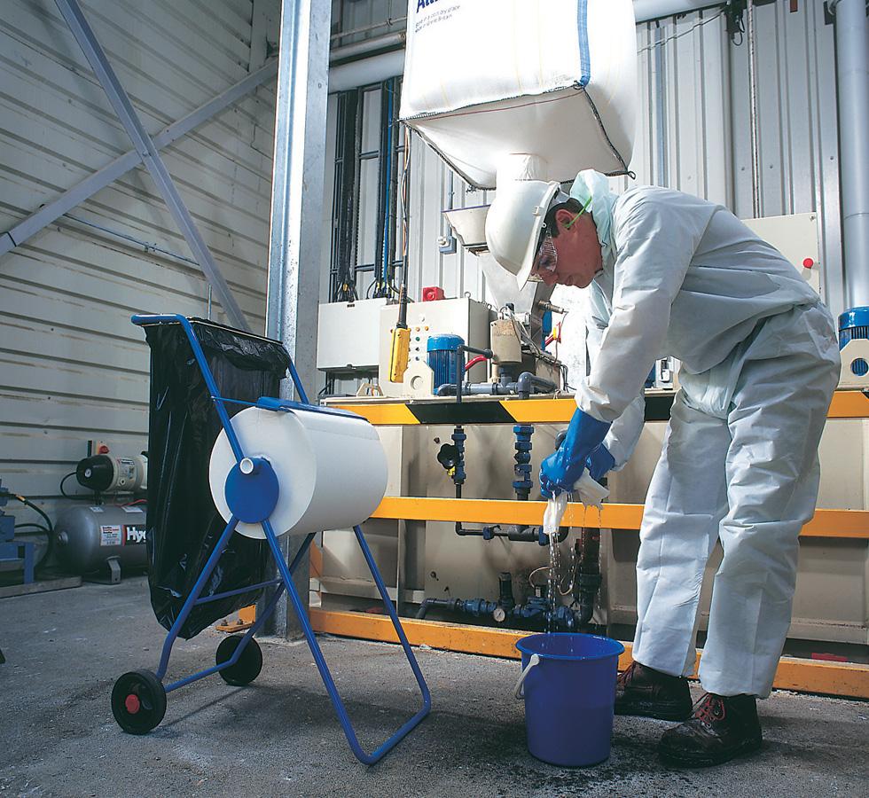 A Man In White Coveralls Wringing a 7454 WYPALL* L40 Wipers, Large Roll on a Blue Dispenser Stand - White - Sentinel Laboratories Ltd