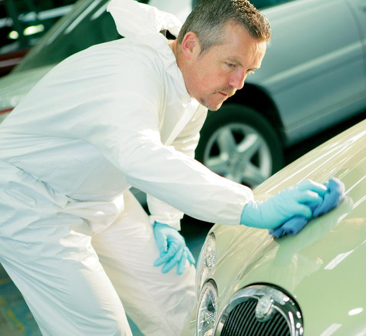 A Man Wearing a White Coverall and Blue Gloves Wiping a Cream Coloured Car Using a Blue 7589 KIMTECH* Surface Preparation Microfibre Cloths - Blue - Sentinel Laboratories Ltd