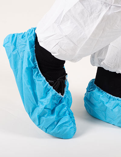 A Person Wearing a Pair of Blue BioClean Durableu™ Disposable Overshoes Over a Pair of Black Shoes - Sentinel Laboratories Ltd