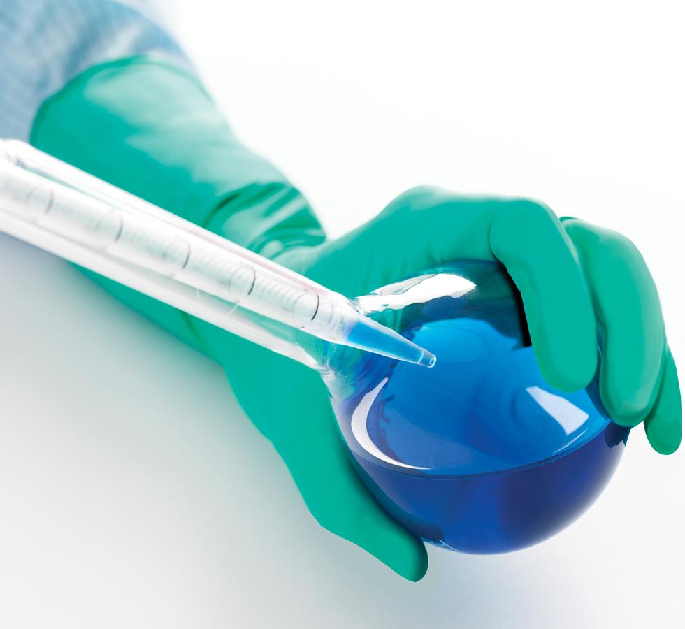 A Person wearing a Green BioClean Emerald Sterile 300mm Length Nitrile Glove Using a Pipette to Dispense Blue Liquid into a Vial - Sentinel Laboratories Ltd