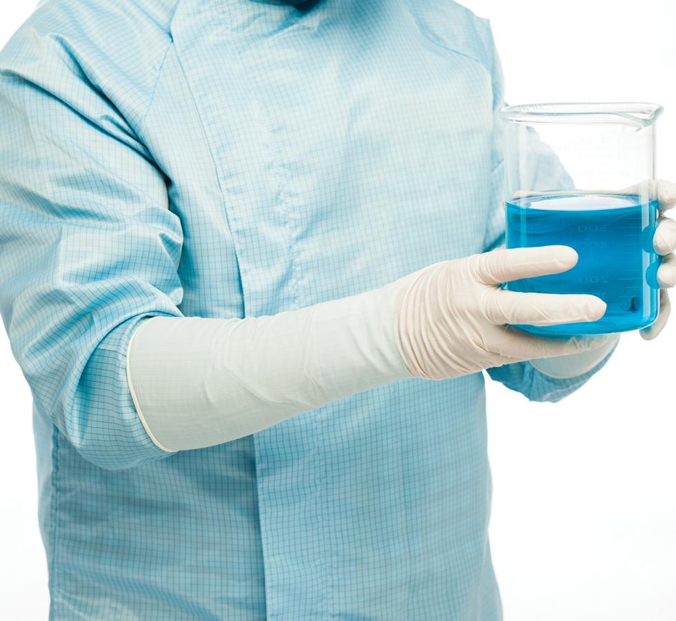 A Person in a Blue Lab Coat Wearing a Pair of White Long Length Cuff BioClean N-Plus™ Sterile 400mm Length Nitrile Gloves Holding a Conical Vial of Blue Liquid - Sentinel Laboratories Ltd
