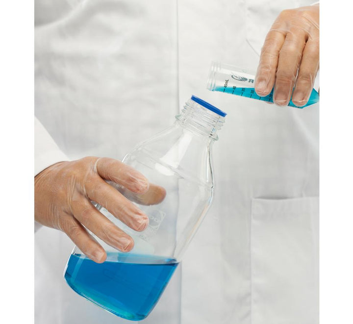 A Person Wearing a White Lab Coat Using a Pair of Clear BioClean Vector™ Non-Sterile 300mm Length Vinyl Gloves Pouring Blue Liquid from a Vial into a Large Jar - Sentinel Laboratories Ltd