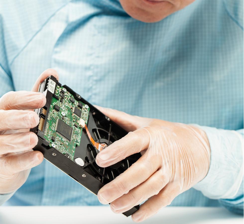 A Man Wearing a Blue Lab Coat using a Pair of Clear BioClean Vista™ Non-Sterile 300mm Length Vinyl Gloves Inspecting a Black Fan Component - Sentinel Laboratories Ltd