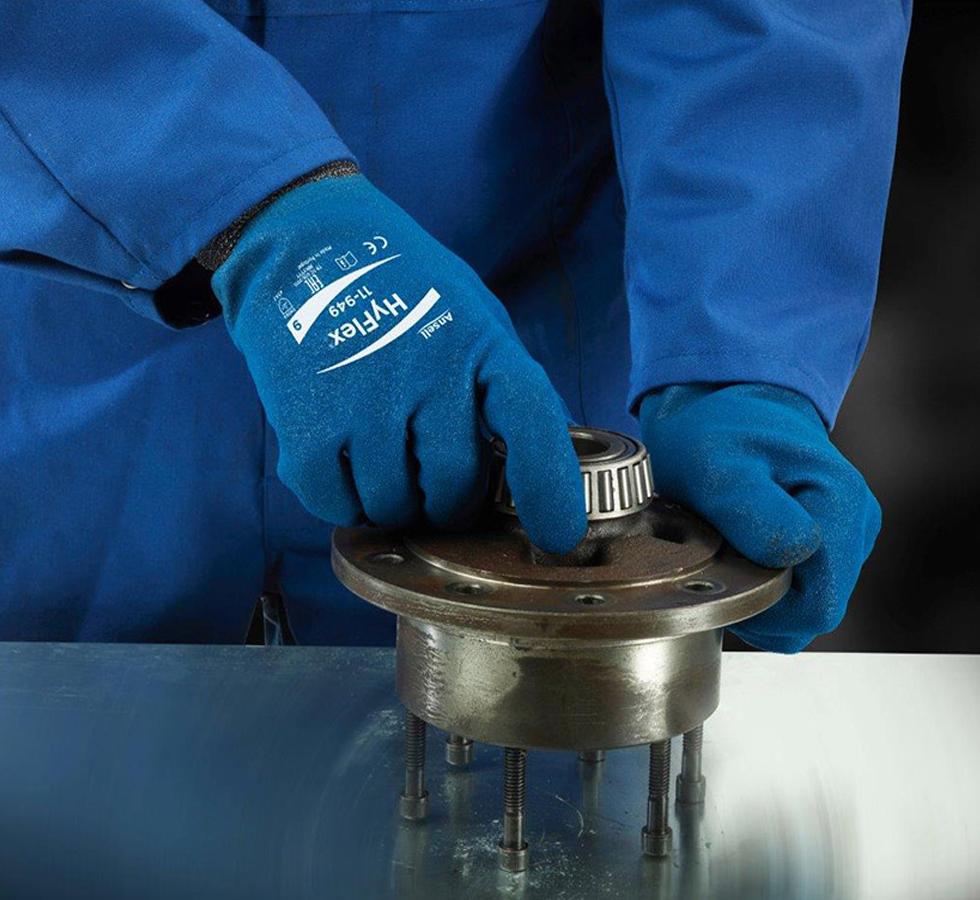 A Man in a Navy Coverall Wearing a Pair of Dark Blue HYFLEX® 11-949 (Previously Nitrotough™ N3500 FD) Gloves Using a Metal Machine - Sentinel Laboratories Ltd