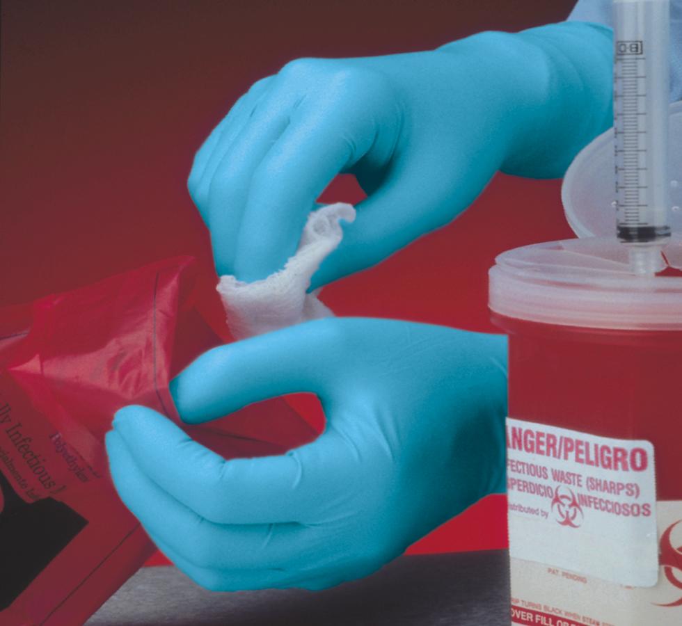 A Person Wearing a Pair of Blue Shield GN70 Hybrid Powder Free Examination Gloves Holding a White Cloth in a Red Room with a Red Sharps Bin in Front - Sentinel Laboratories Ltd