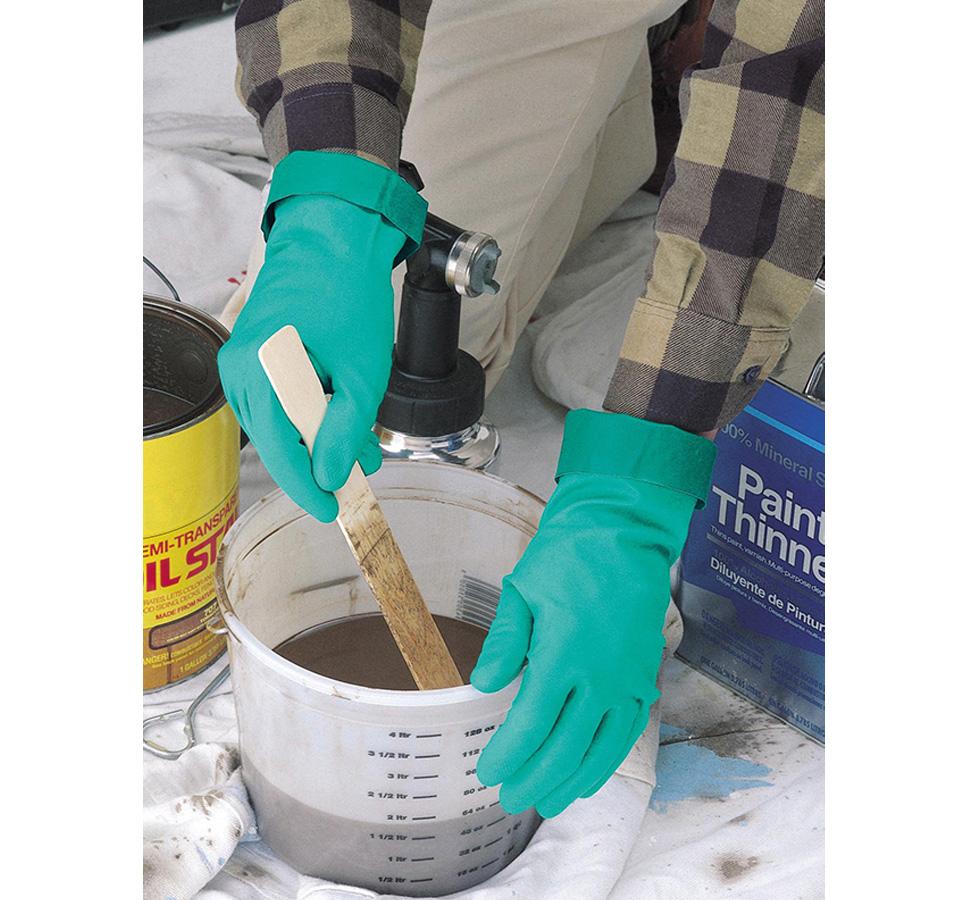 A Person in a Chequered Shirt Wearing a Pair of Green Showa Best 737 Nitri-Solve® Folded Cuffs Mixing Brown Liquid in a Bucket - Unlined 0,56mm thick, 380mm long - Sentinel Laboratories Ltd